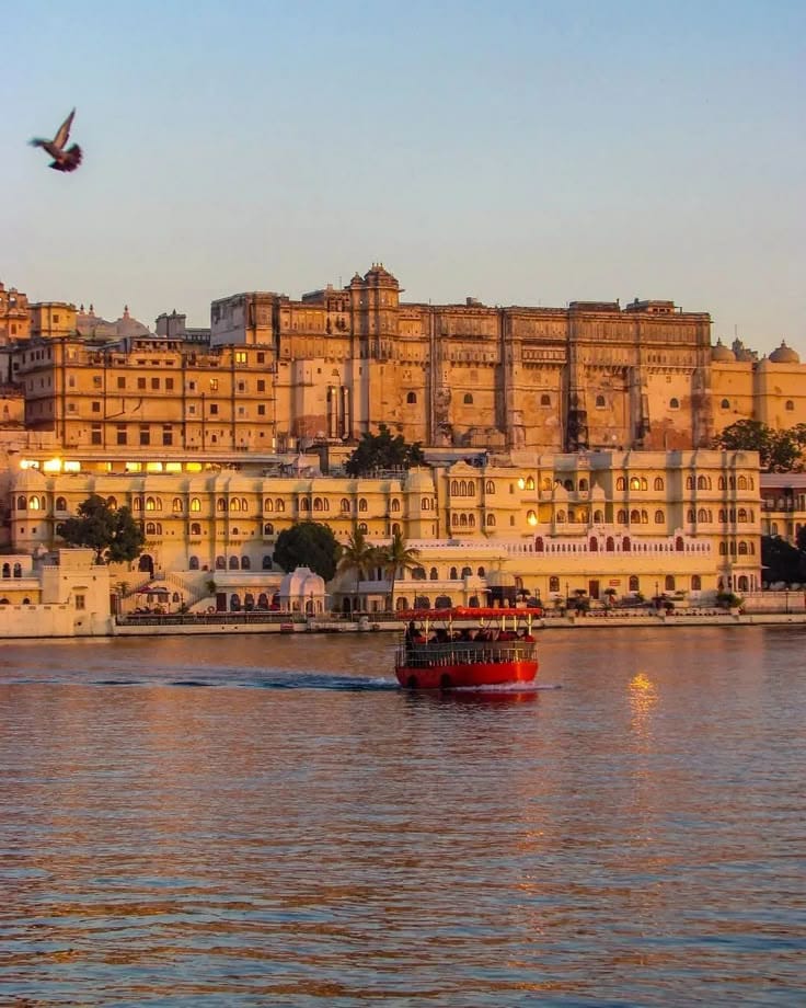 City Palace in Udaipur with a boat on the lake at sunset