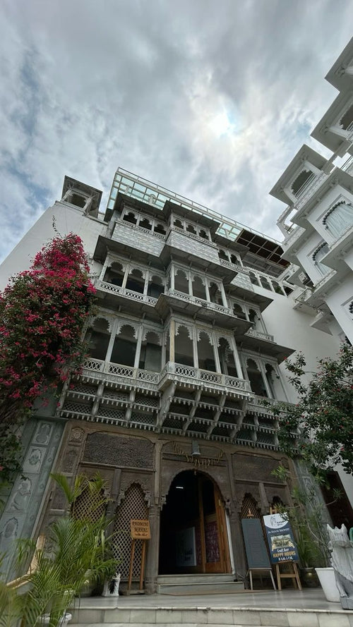 Traditional Indian building with intricate architecture and a cloudy sky.