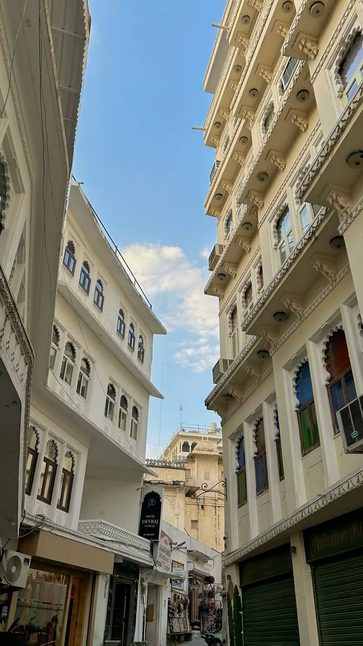 Tight street between tall buildings with a clear blue sky.