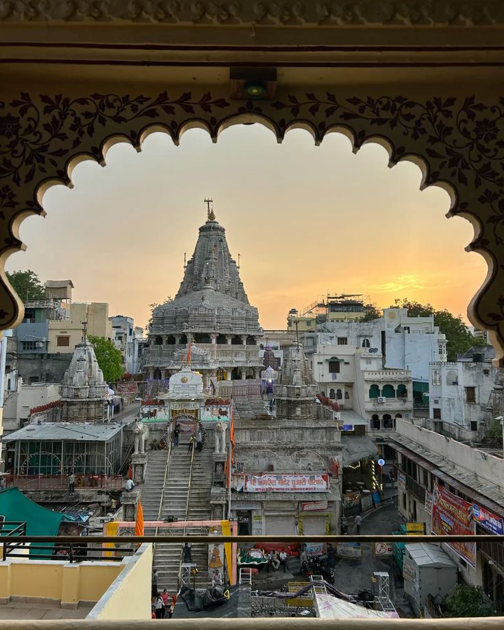 Temple complex with a tower at sunset, viewed through an ornate archway.